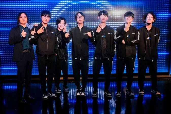 DetonatioN FocusMe League of Legends team posing together on stage in black jackets after qualifying for the Worlds Group Stage